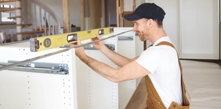 Technician leveling white kitchen cabinets during installation