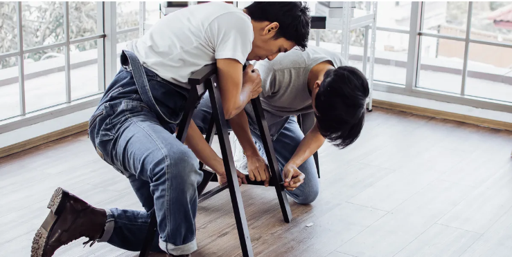 Two technicians assembling office furniture in a bright workspace