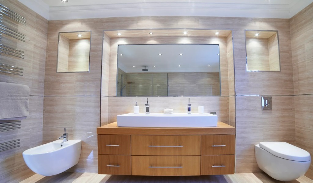 Luxury bathroom with floating wood vanity, white vessel sink, beige stone tile, and wall-hung fixtures