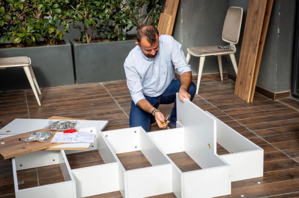 On-site furniture assembly of a white modular shelving unit on a tiled patio